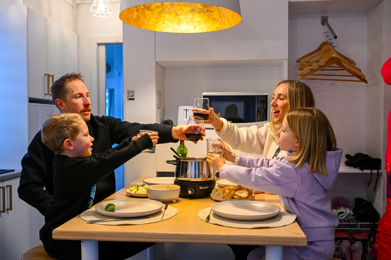 Famille en train de faire un toast à table dans la cuisine d'une Coolbox.